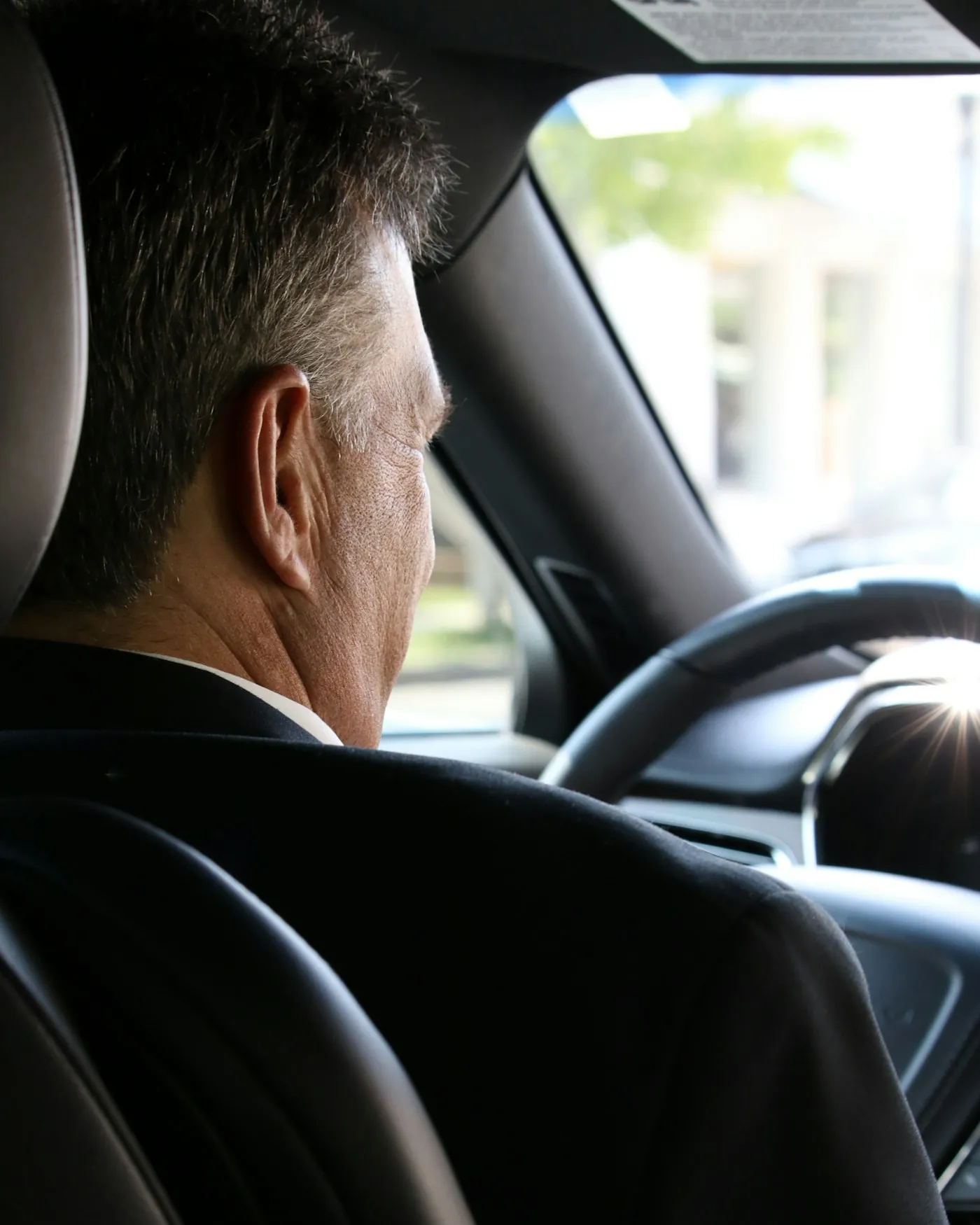Chauffeur in a dark suit at the wheel of a luxury car